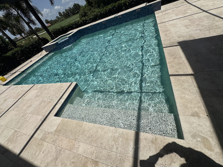 Clear turquoise residential pool with travertine deck and sun shelf